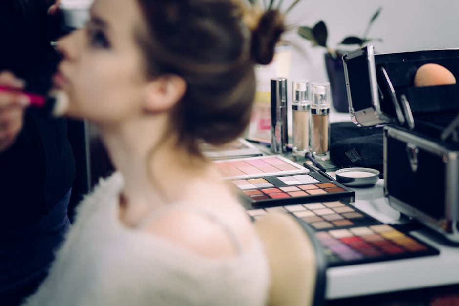 A woman receiving professional makeup in a studio with various cosmetics in focus.